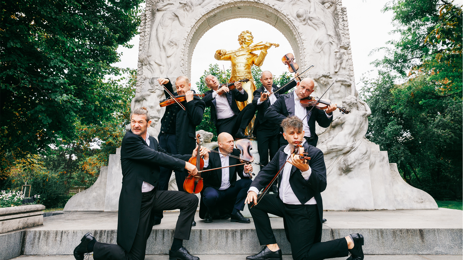 Portrait der Bandmitglieder vor einer Statue